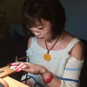 Metalsmithing student using the jewelers saw to cut out her pendant design