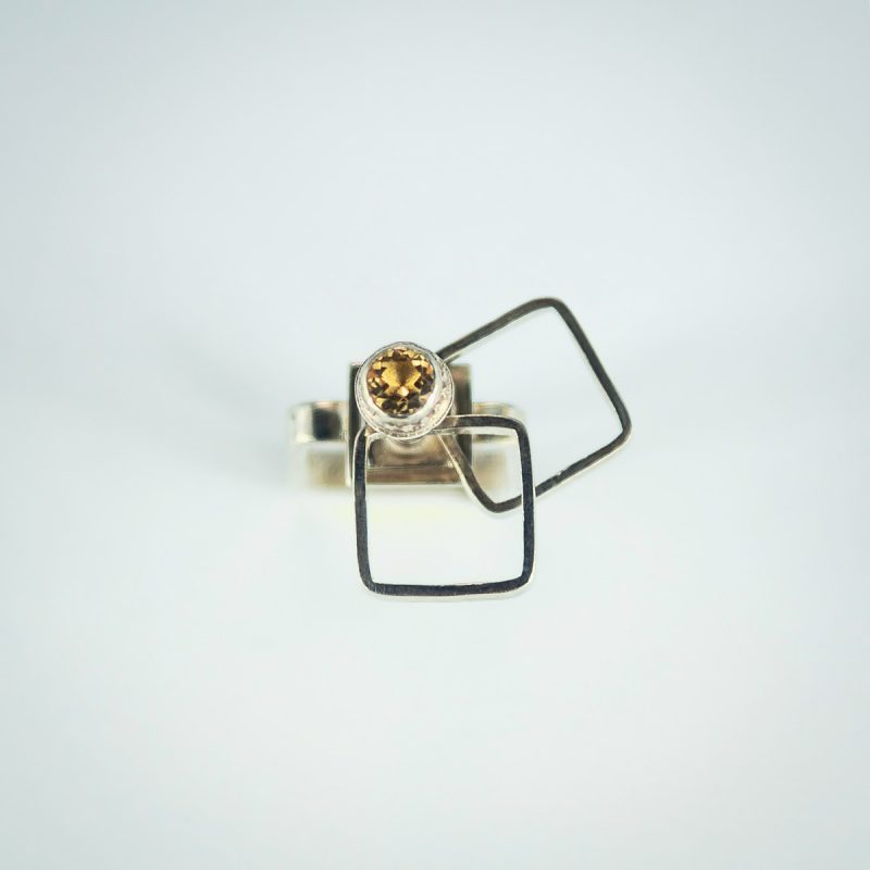 This is a stunning Kinetic Square Cocktail Ring! It has a square ring shank, sparkling citrine stone set in a decorative bezel, 2 square rings on top that like to spin around and will keep you and everyone around you mesmerized! Made from sterling silver and has a polished finish for a luscious look. Top view.