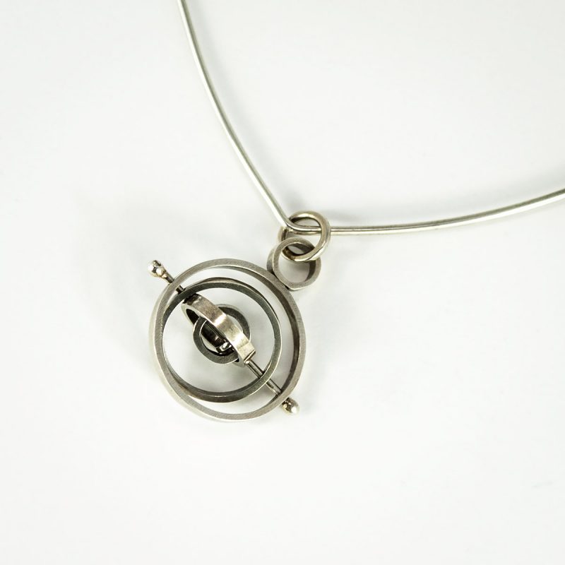 This sleek Orbital Kinetic Silver Pendant has concentric circles that slide and spin independently along the silver post. The pendant is oxidized and polished. A fabulous piece to fidget with! Top view.